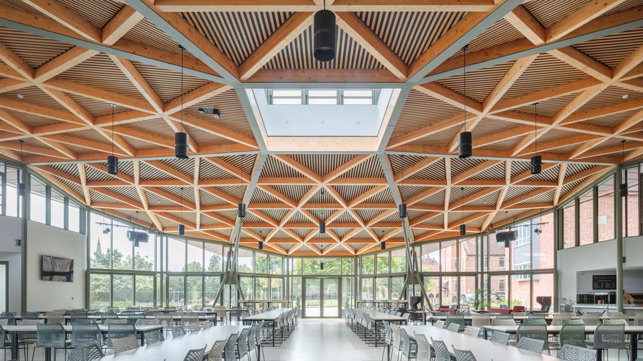 David Morley Architects LLP — View of the interior of the pavilion, featuring the spacious dining space and lattice glulam interior roof structure.